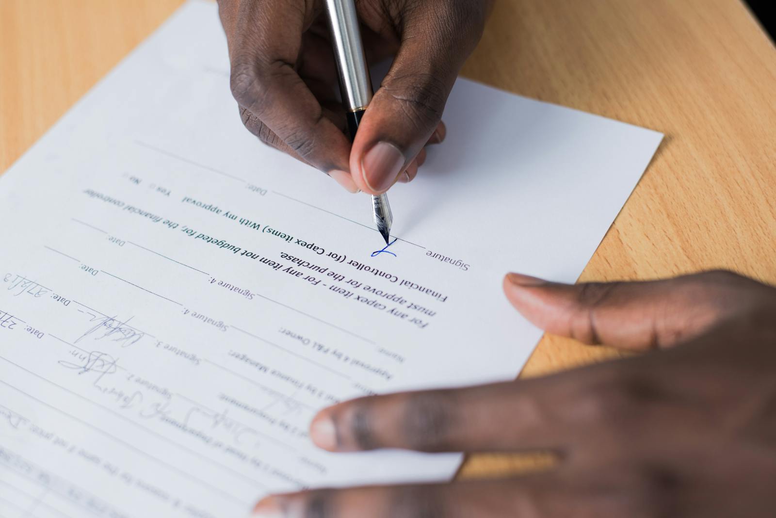 Hand signing a business contract on a desk