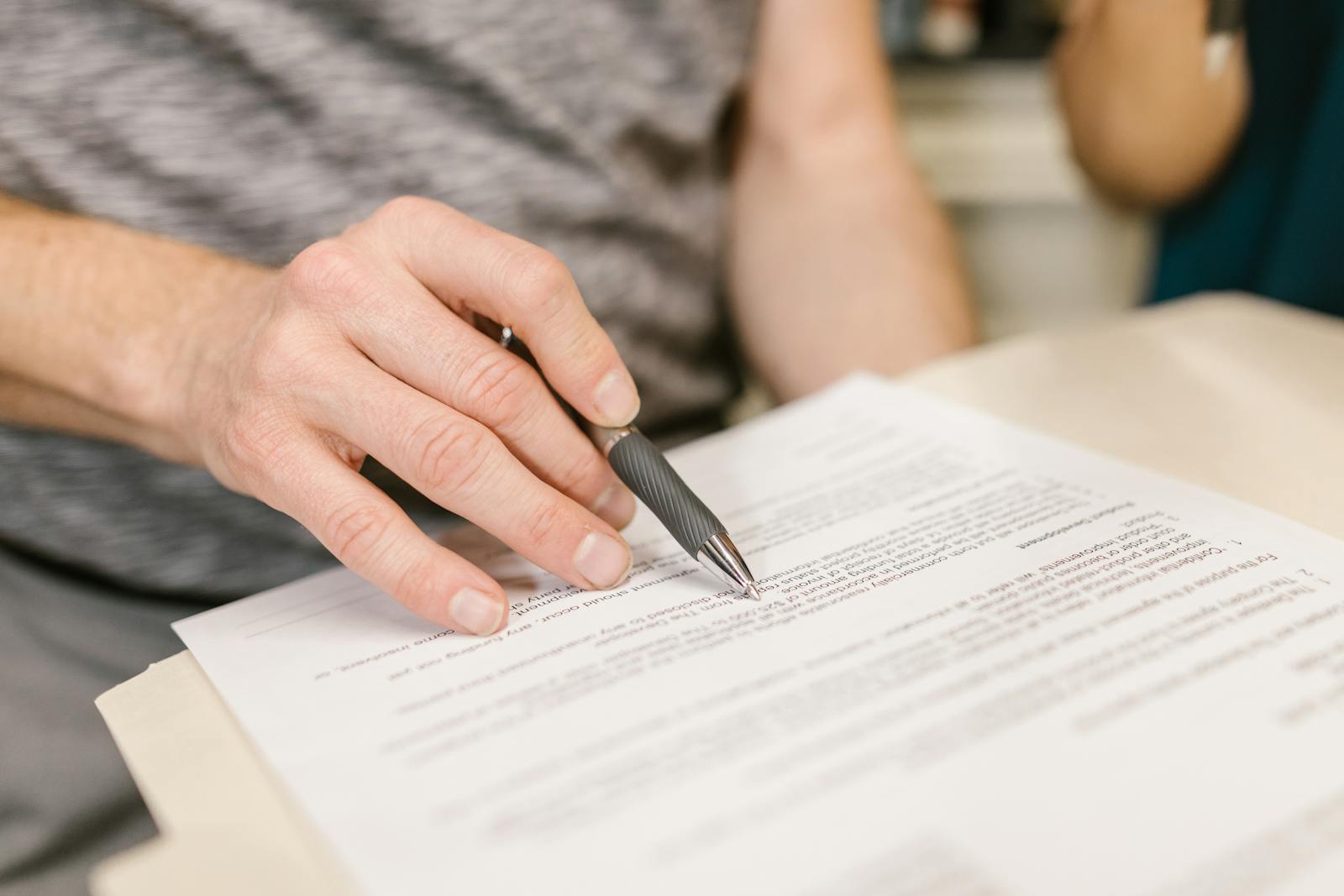 Close-up of a hand signing a legal document with a pen